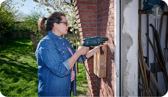 kobieta wiercąca wiertarką udarową w cegle